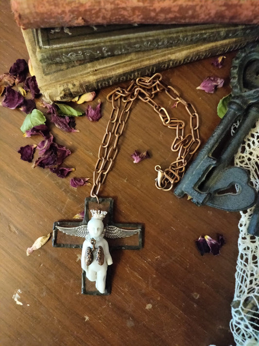 Charles' Last Breath necklace flat lay, black cross pendant with copper oval-link chain resting on a book beside an antique skeleton key, lace, and dried rose petals