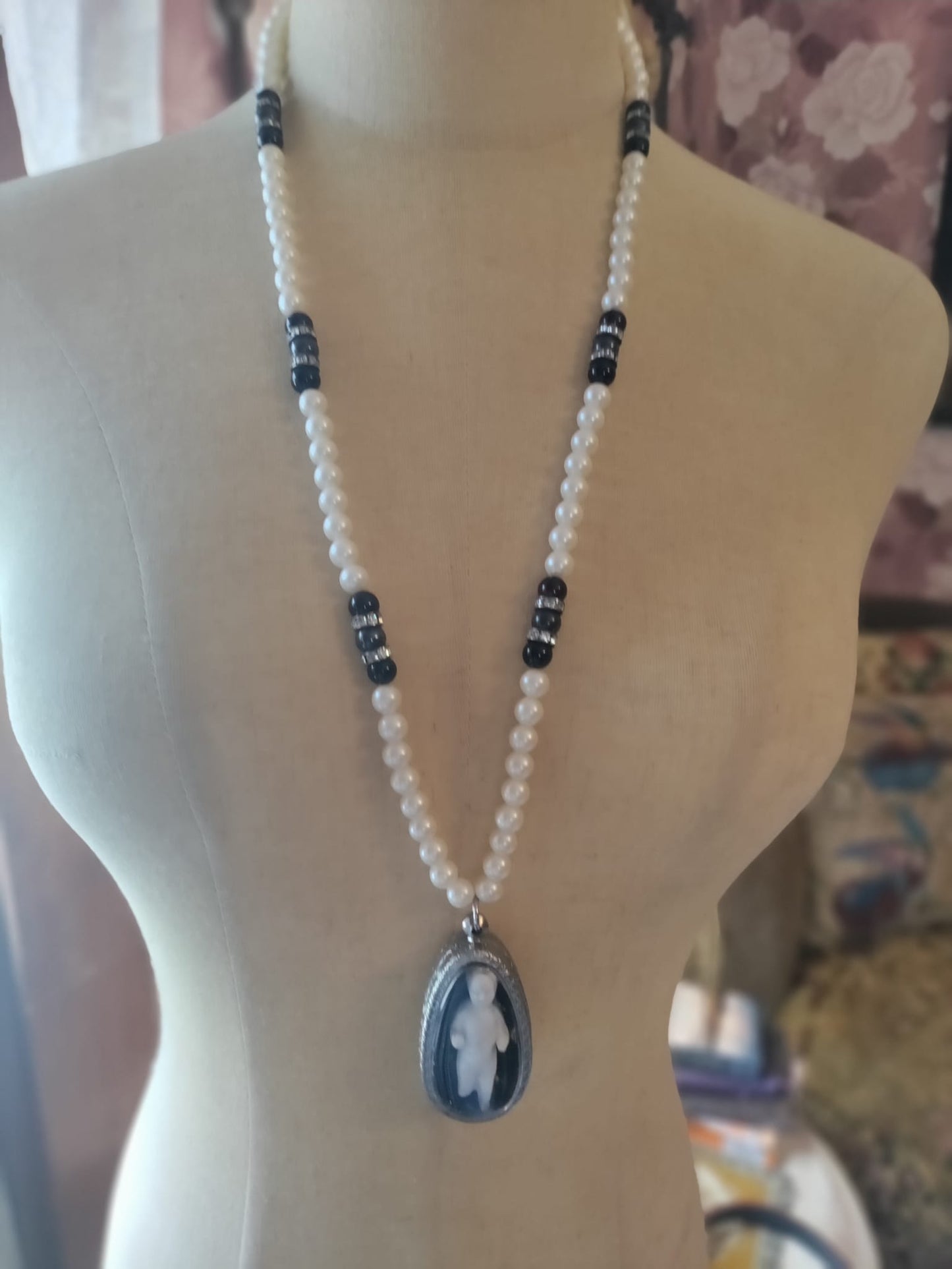 Reliquary Frozen Charles necklace worn on mannequin, full-length pearl and black bead chain with rhinestone spacers and oval silver pendant