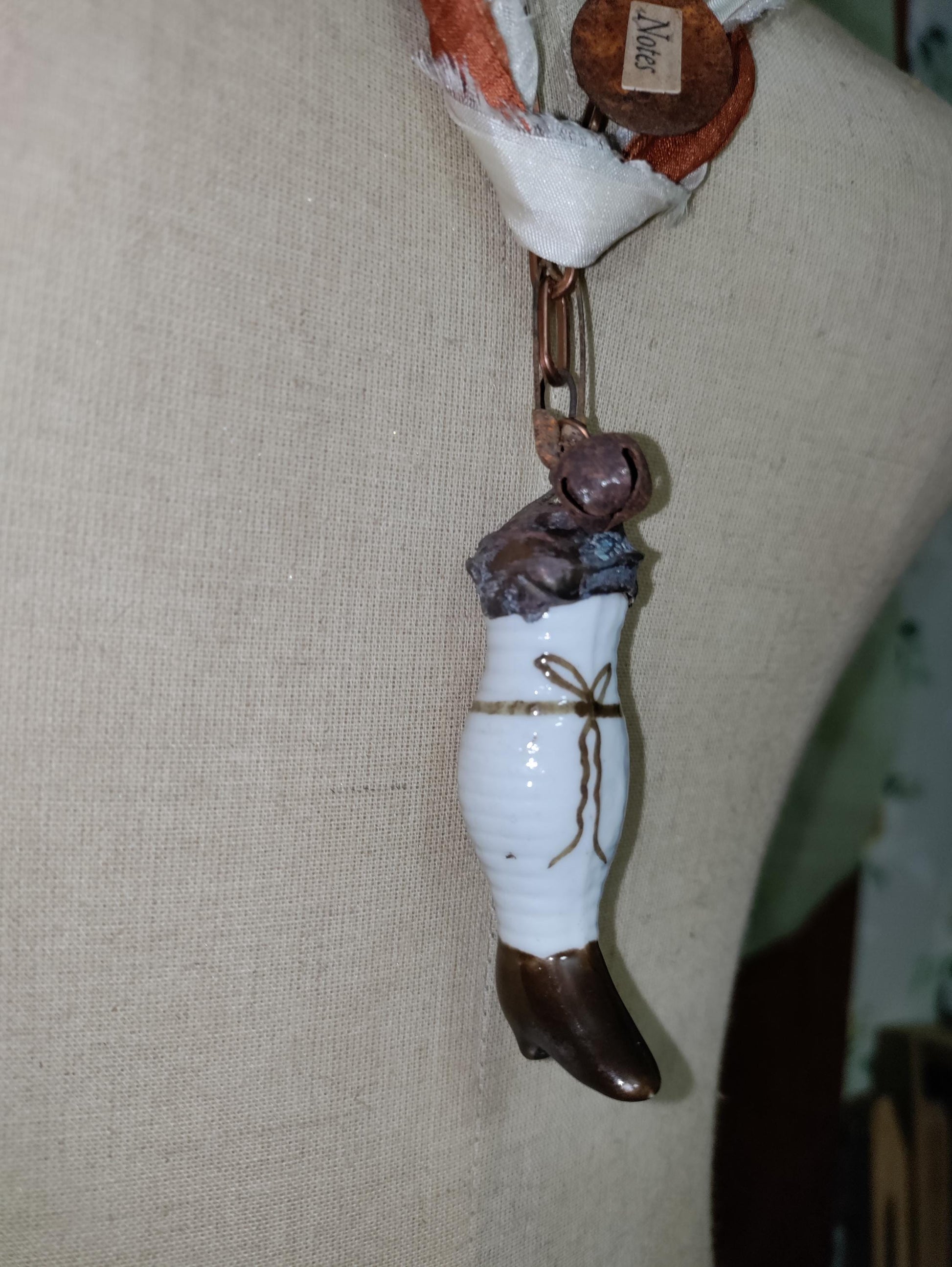 Porcelain antique doll leg, accented with rusted charms.