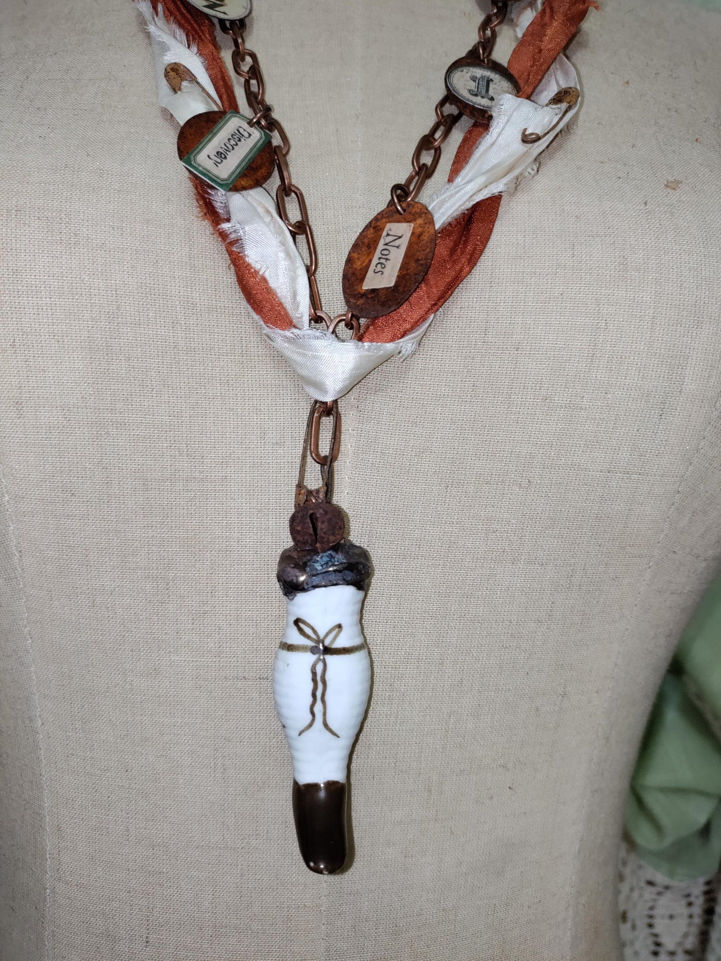 Porcelain antique doll leg, accented with rusted charms.