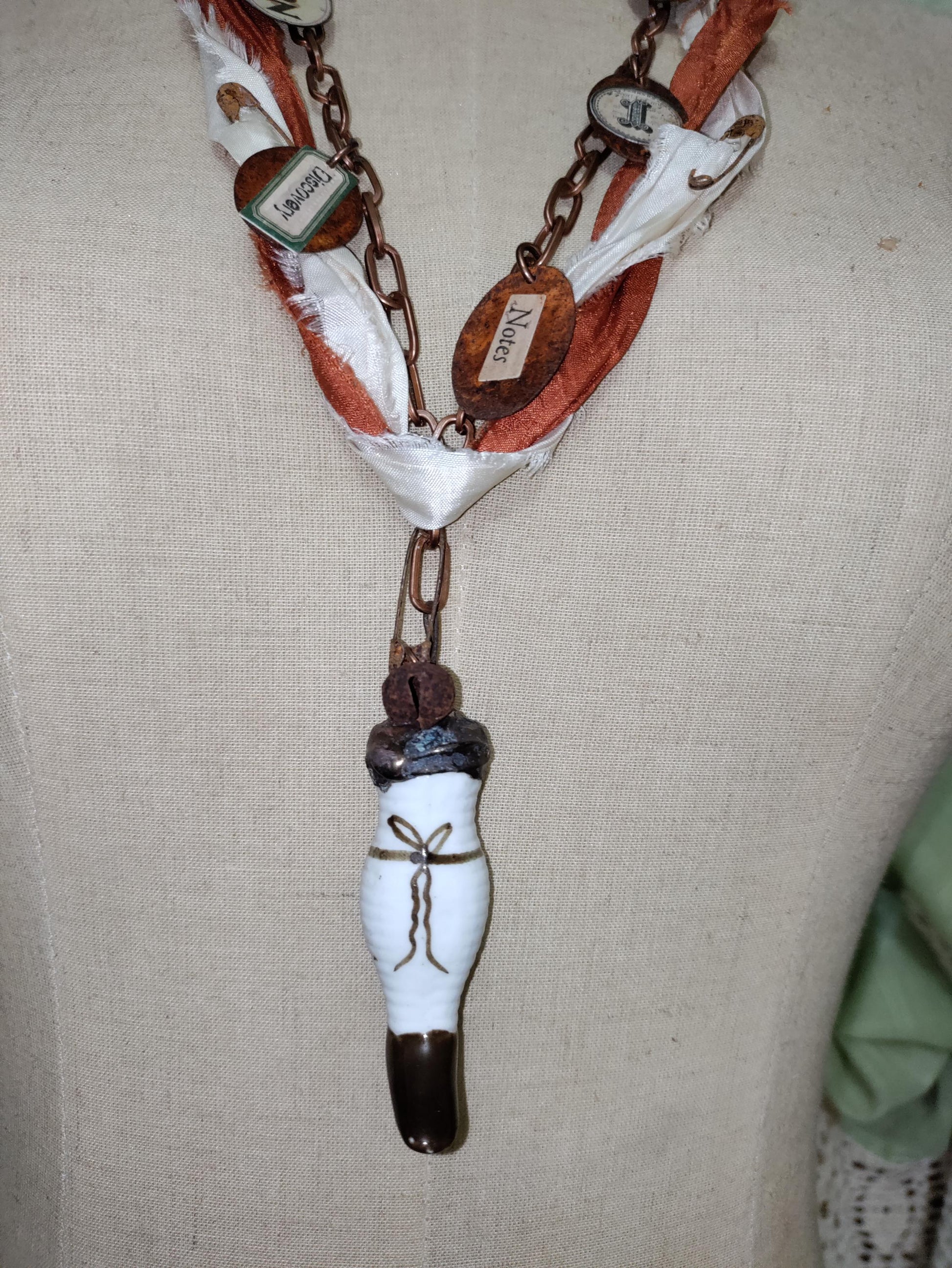 Porcelain antique doll leg, accented with rusted charms.