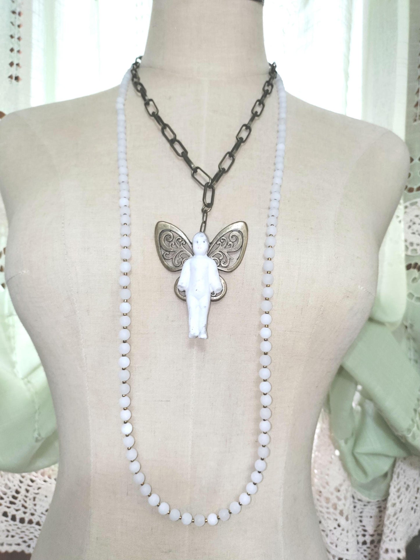 Frozen Charlotte with butterfly wings, with white frosted beads, necklace.