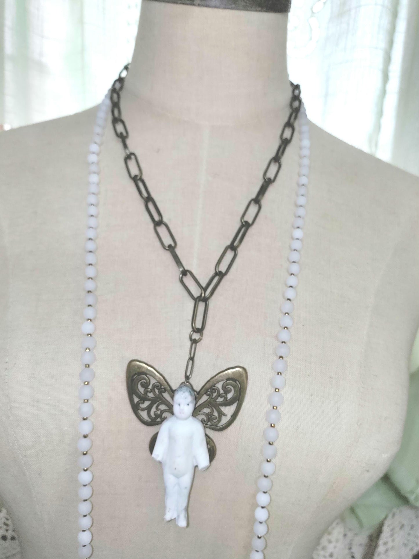 Frozen Charlotte with butterfly wings, with white frosted beads, necklace.
