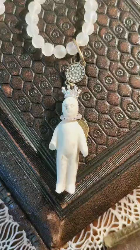 Video of the Frozen Charlotte necklace showing the frosted white bead strand and crowned bisque doll pendant from multiple angles